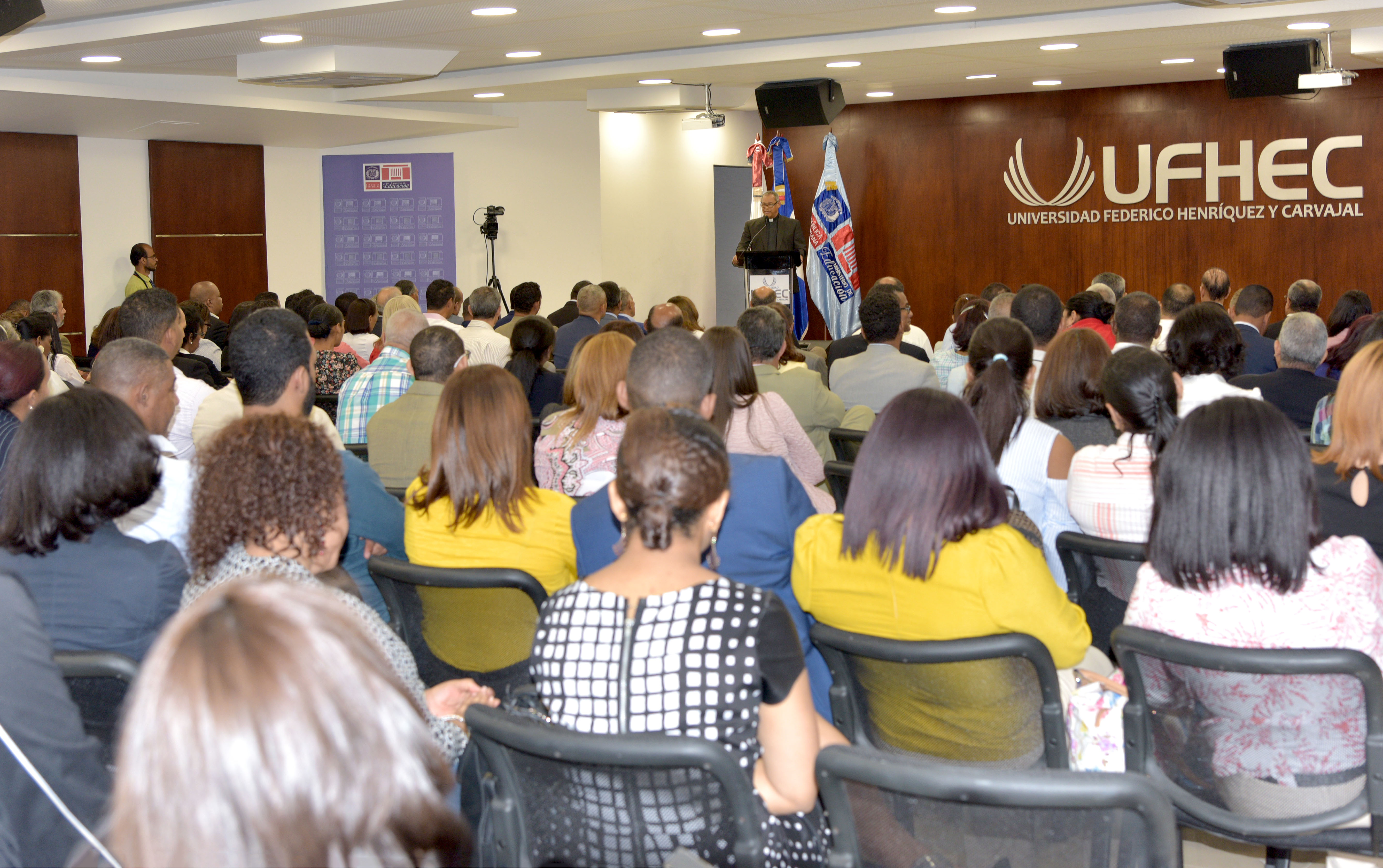  imagen Ministro Andr&eacute;s Navarro de pie en podium dirigiendo discurso a personas en auditorium de la universidad Federico Henr&iacute;quez y Carvajal&nbsp; 