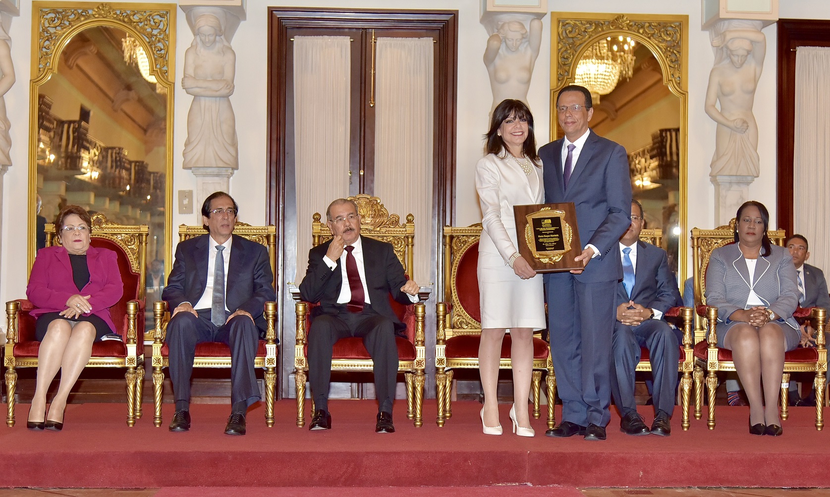  imagen De derecha a izquierda sentados, ministros Alejandrina Germ&aacute;n, Gustavo Montalvo y Presidente Danilo Medina. De pie a la derecha Ministro Antonio Pe&ntilde;a Mirabal entrega reconocimiento a&nbsp;Mar&iacute;a Marinick. 