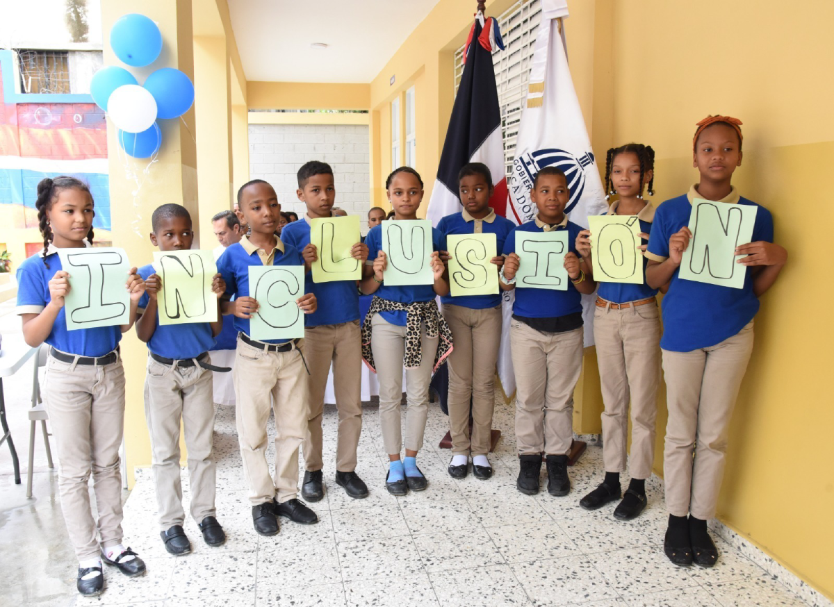  imagen Randa Rosario y Antonio Marcelino junto a dos estudiantes, durante corte de cinta en la entrada del aula. 