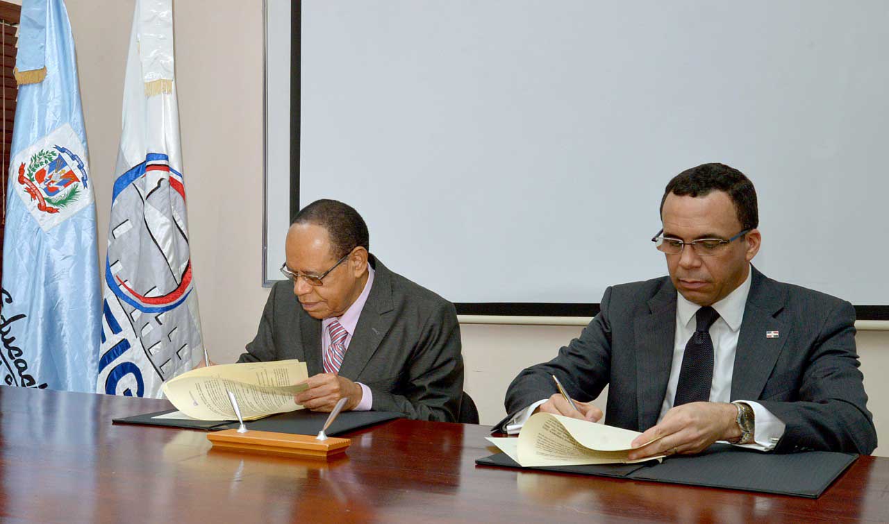  imagen Ministro Andr&eacute;s Navarro y Director Lidio Cadet mientras firman acuerdo. 