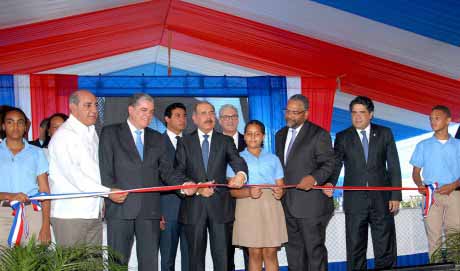  imagen Presidente Danilo Medina mientras corta cinta en acto de inauguraci&oacute;n, le acompa&ntilde;an varias personalidades. 