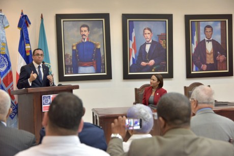  imagen Ministro Andr&eacute;s Navarro hablando de pie desde podium se dirige a miembros del C&iacute;rculo de Locutores que est&aacute;n sentados en sillas frente a el. 