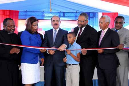  imagen Presidente Danilo Medina mientras corta cinta en acto de inauguraci&oacute;n, le acompa&ntilde;an varias personalidades. 